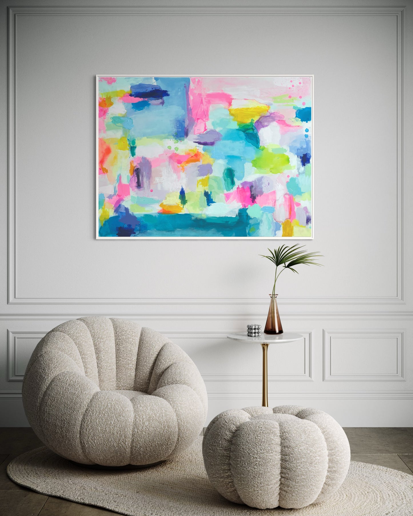 The Dolly Original Abstract Painting by Sarah Henry as part of the Happy Art Collection, shown hanging on a white wall with trim molding above a cream colored boucle chair and ottoman aside a cocktail table with a palm leaf in a vase in a hallway.