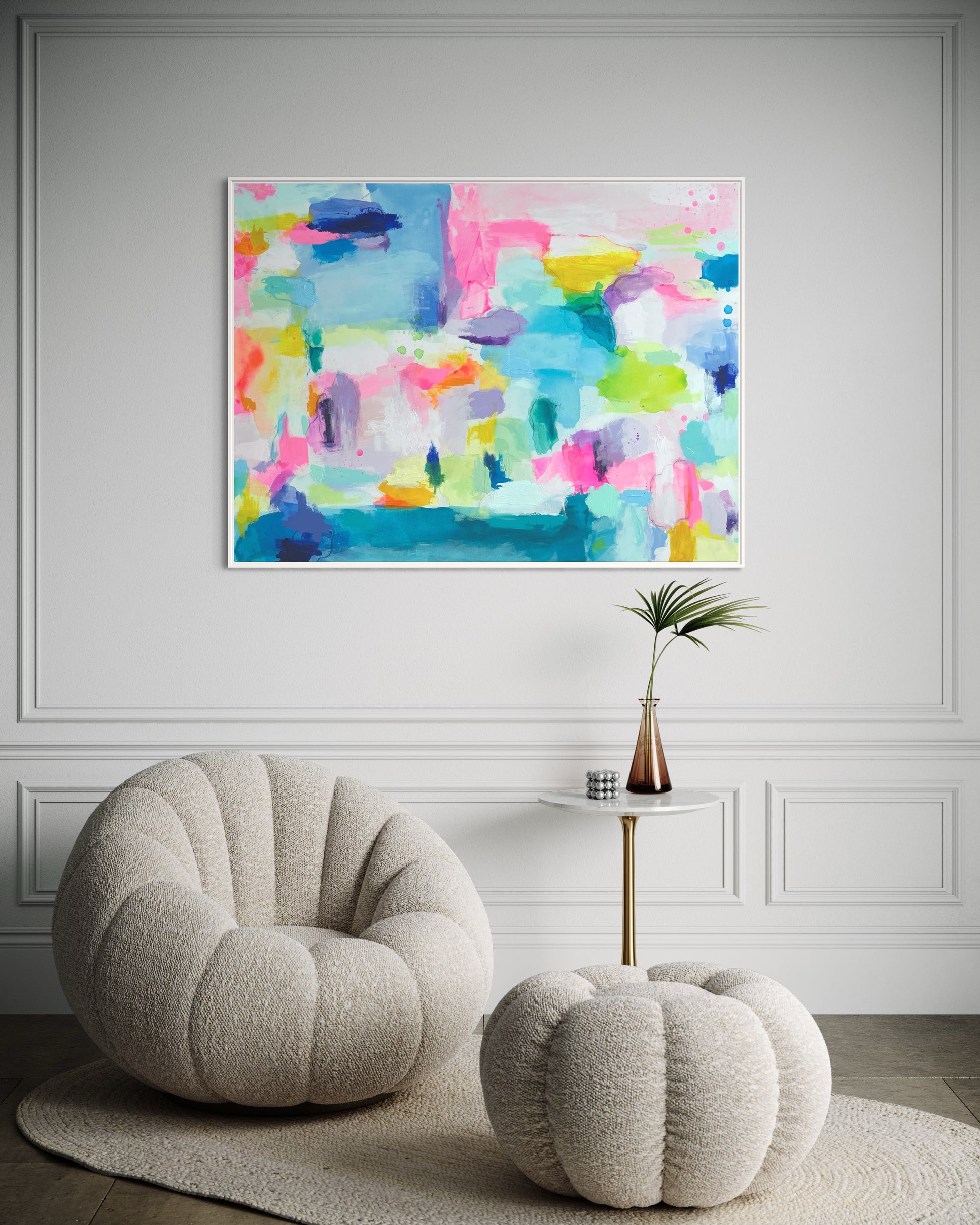 The Dolly Original Abstract Painting by Sarah Henry as part of the Happy Art Collection, shown hanging on a white wall with trim molding above a cream colored boucle chair and ottoman aside a cocktail table with a palm leaf in a vase in a hallway.