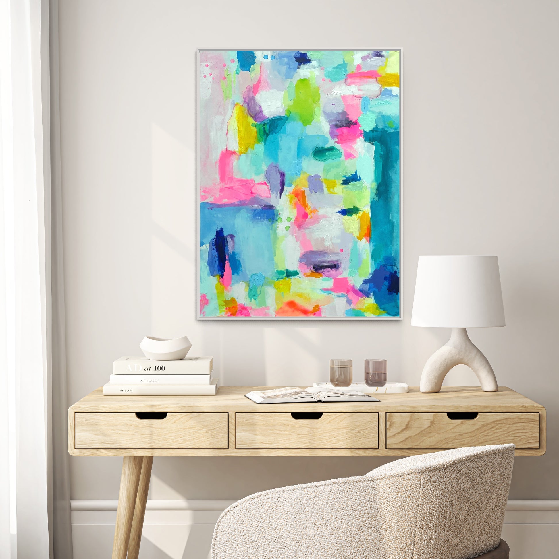 The Dolly Original Abstract Painting by Sarah Henry as part of the Happy Art Collection, shown on a white wall hanging above a three drawer modern desk with monochromatic white decor and a white boucle office chair.