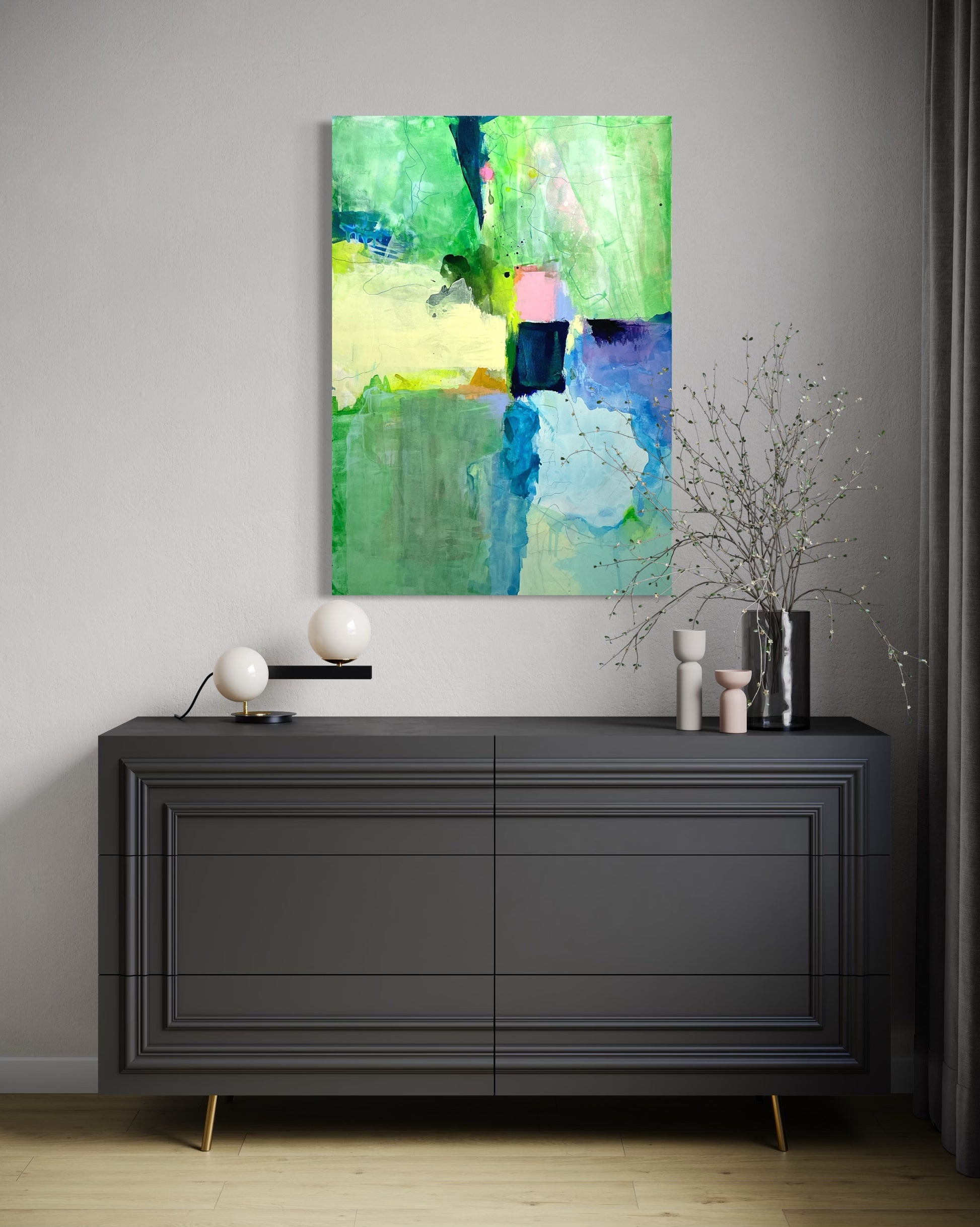 Abstract painting on a wall above a black dresser with decorative items.