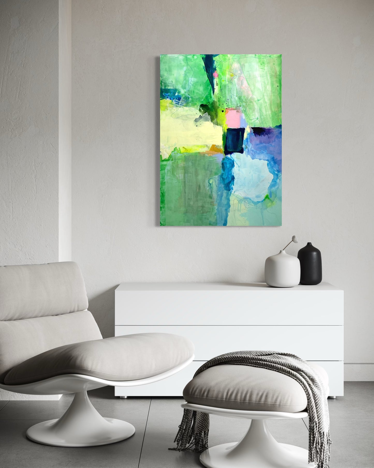 Abstract painting on a wall above a white cabinet in a minimalist iving room.