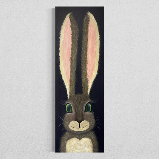 A 12"x36" oblong abstract acrylic painting with a cartoon style hare rabbit bunny with dazzling green eyes, gray and brown fur, pink ears, long eyelashes, on a navy blue background hangs on a white wall.