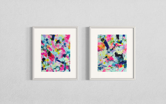 A modern gallery collection of abstract paintings featuring vibrant splashes of color, including pink, blue, yellow, green, purple and white. Each canvas is filled with expressive, energetic brushstrokes and layered paint splatters, creating a dynamic and contemporary composition. The affordable wall decor is arranged side by side on a white wall, forming a cohesive yet varied visual experience.