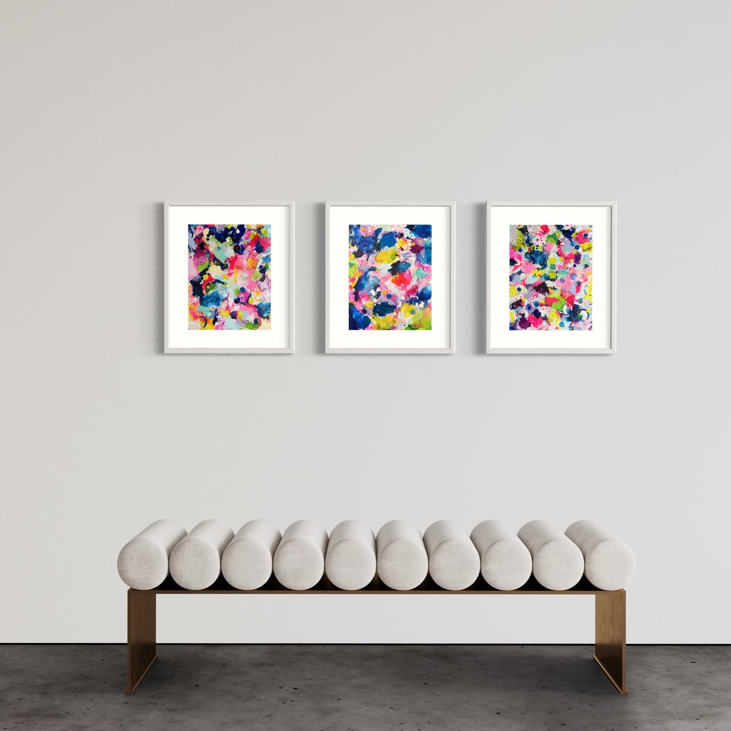 A modern gallery collection of abstract paintings featuring vibrant splashes of color, including pink, blue, yellow, green, purple and white. Each canvas is filled with expressive, energetic brushstrokes and layered paint splatters, creating a dynamic and contemporary composition. The affordable wall decor is arranged side by side on a white wall, forming a cohesive yet varied visual experience.