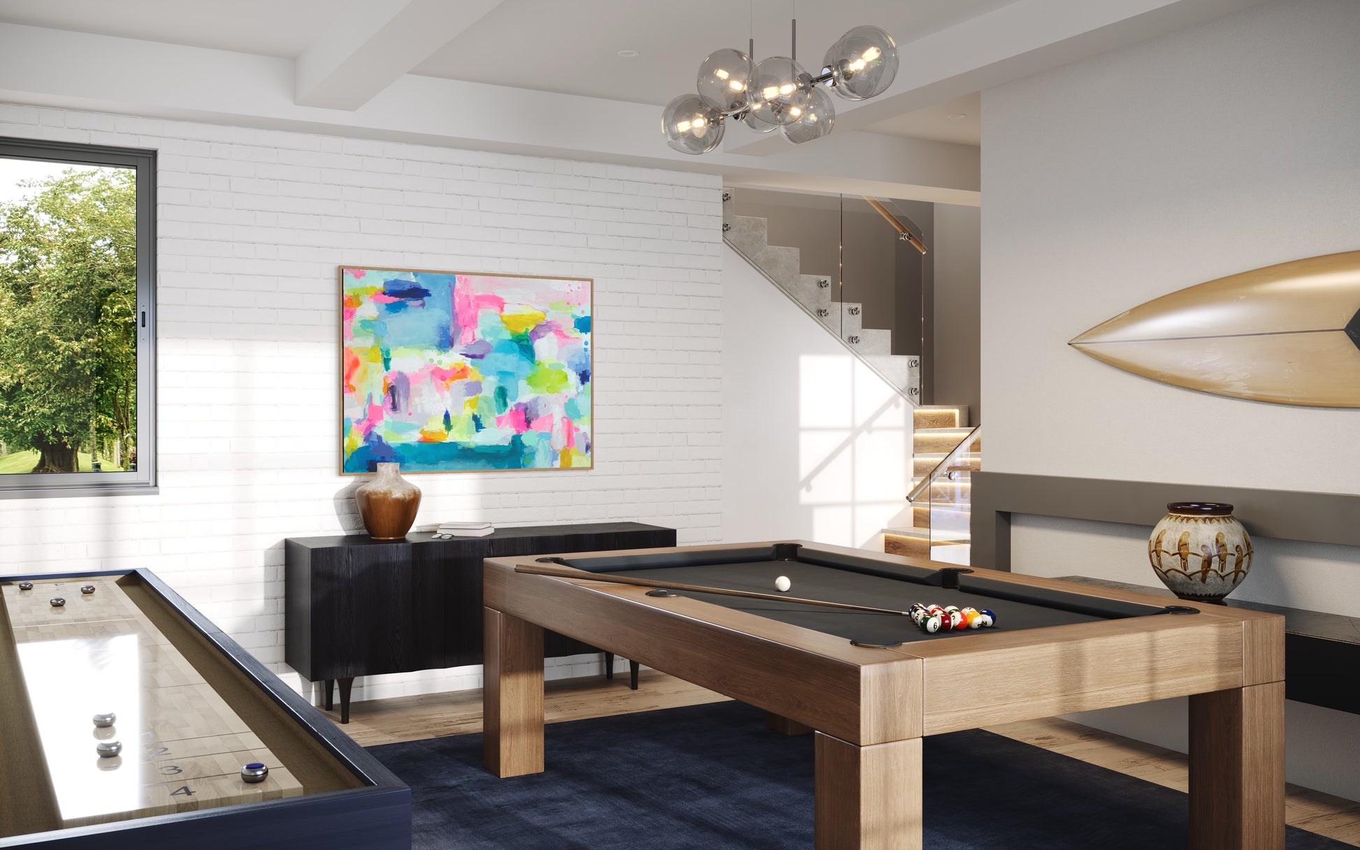The Dolly Original Abstract Painting by Sarah Henry as part of the Happy Art Collection, shown hanging on a wall with shiplap in a game room with a pool table, a foosball table, and a surfboard with a bubble chandelier light.