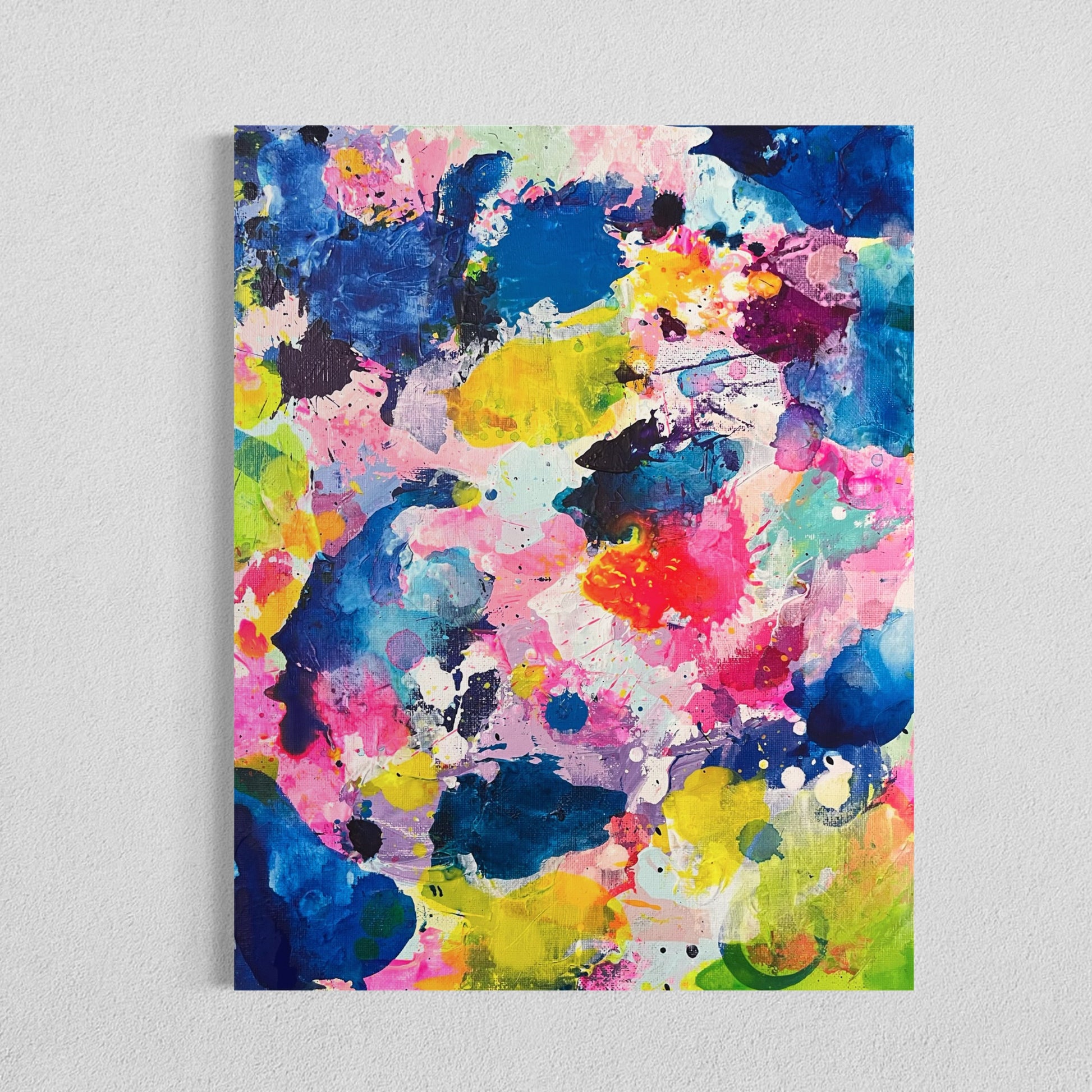 A modern gallery collection of abstract paintings featuring vibrant splashes of color, including pink, blue, yellow, green, purple and white. Each canvas is filled with expressive, energetic brushstrokes and layered paint splatters, creating a dynamic and contemporary composition. The affordable wall decor is arranged side by side on a white wall, forming a cohesive yet varied visual experience.