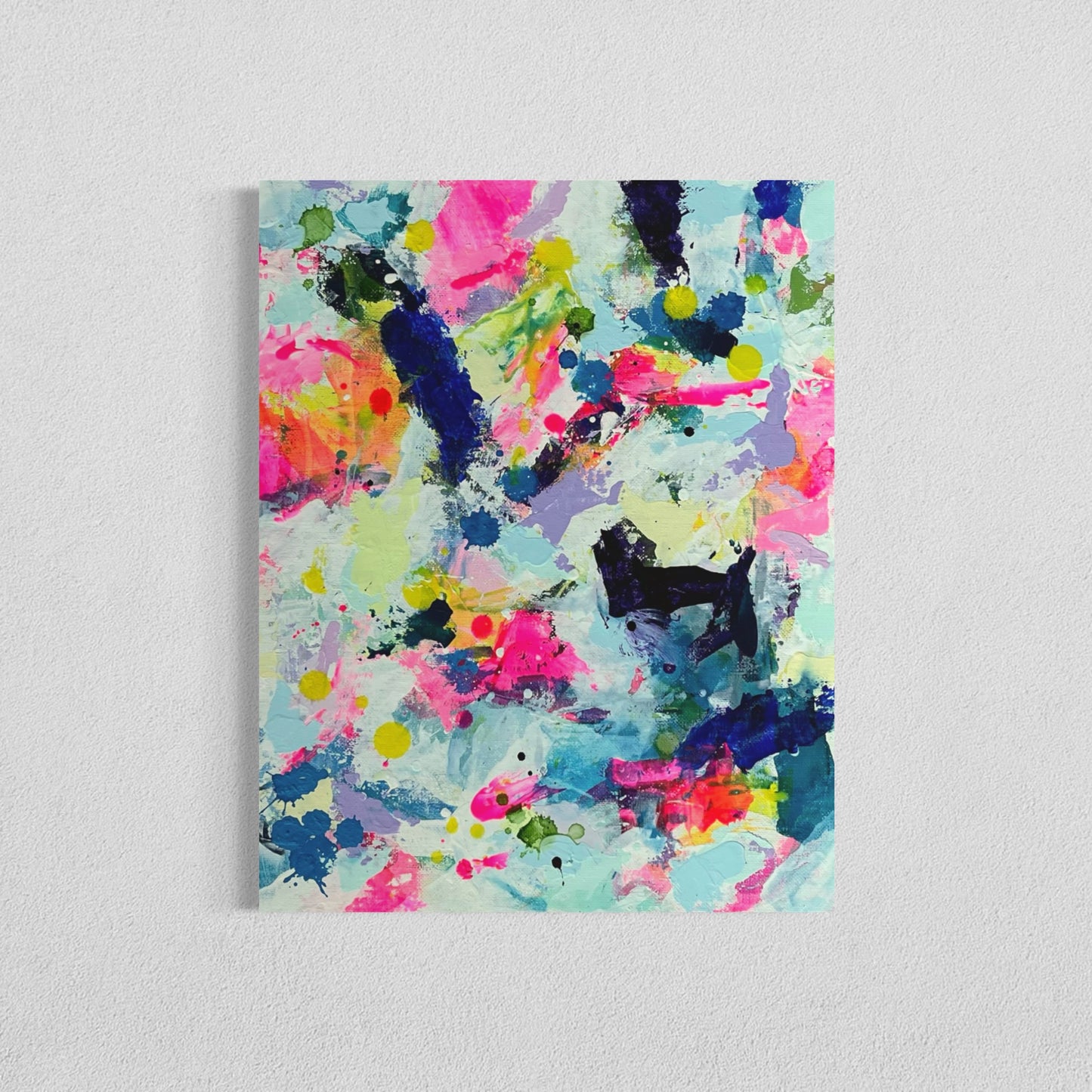 A modern abstract painting featuring vibrant splashes of color, including pink, blue, yellow, green, purple and white. Each canvas is filled with expressive, energetic brushstrokes and layered paint splatters, creating a dynamic and contemporary composition. The affordable wall decor is on a white wall, forming a cohesive yet varied visual experience.