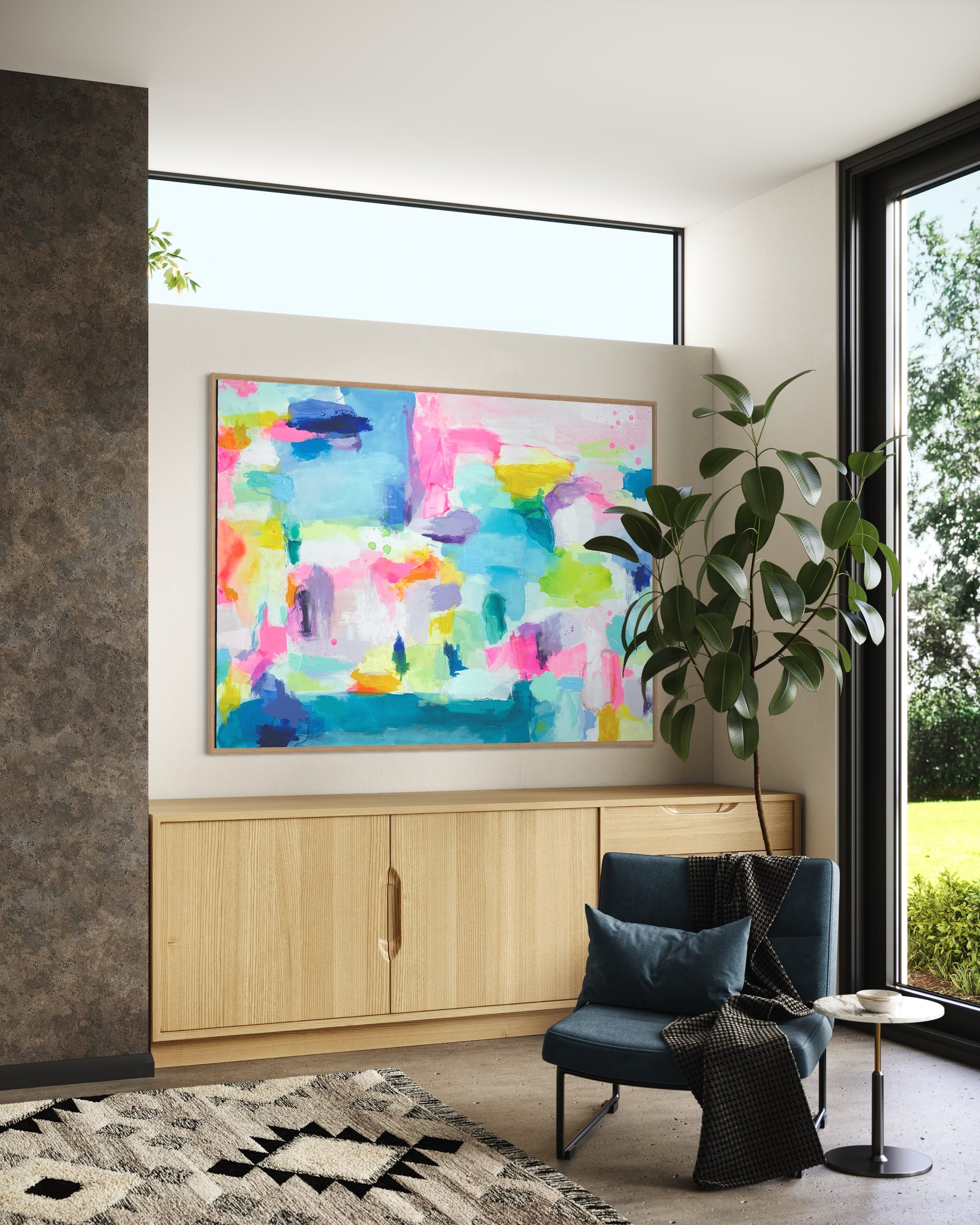 The Dolly Original Abstract Painting by Sarah Henry as part of the Happy Art Collection, shown in a seating area hanging on a white wall above a built in pine colored cabinet with a blue modern chair and cocktail table.