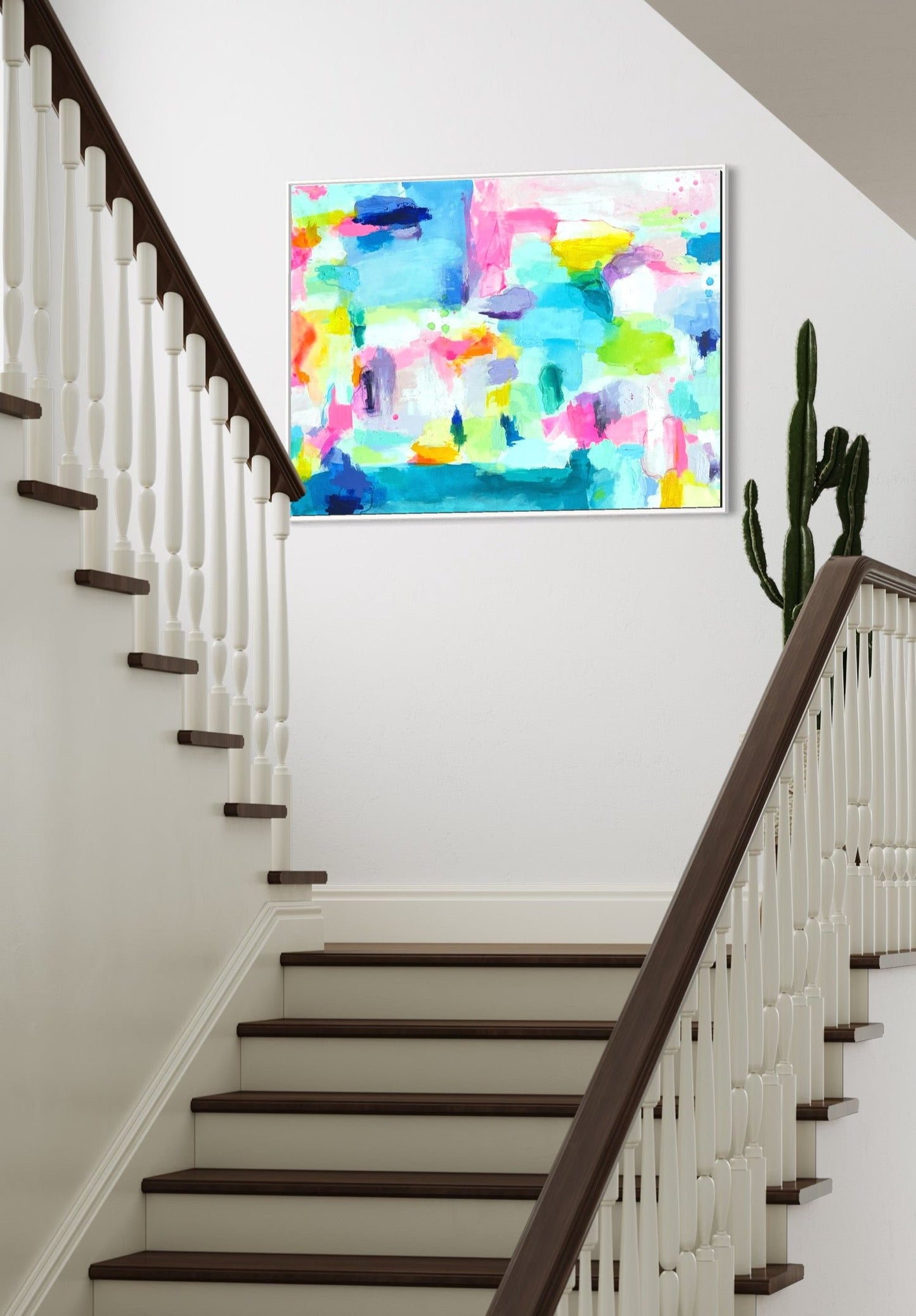 The Dolly Original Abstract Painting by Sarah Henry as part of the Happy Art Collection, shown on a white wall of a residential stair landing with a cactus plant beside the painting.