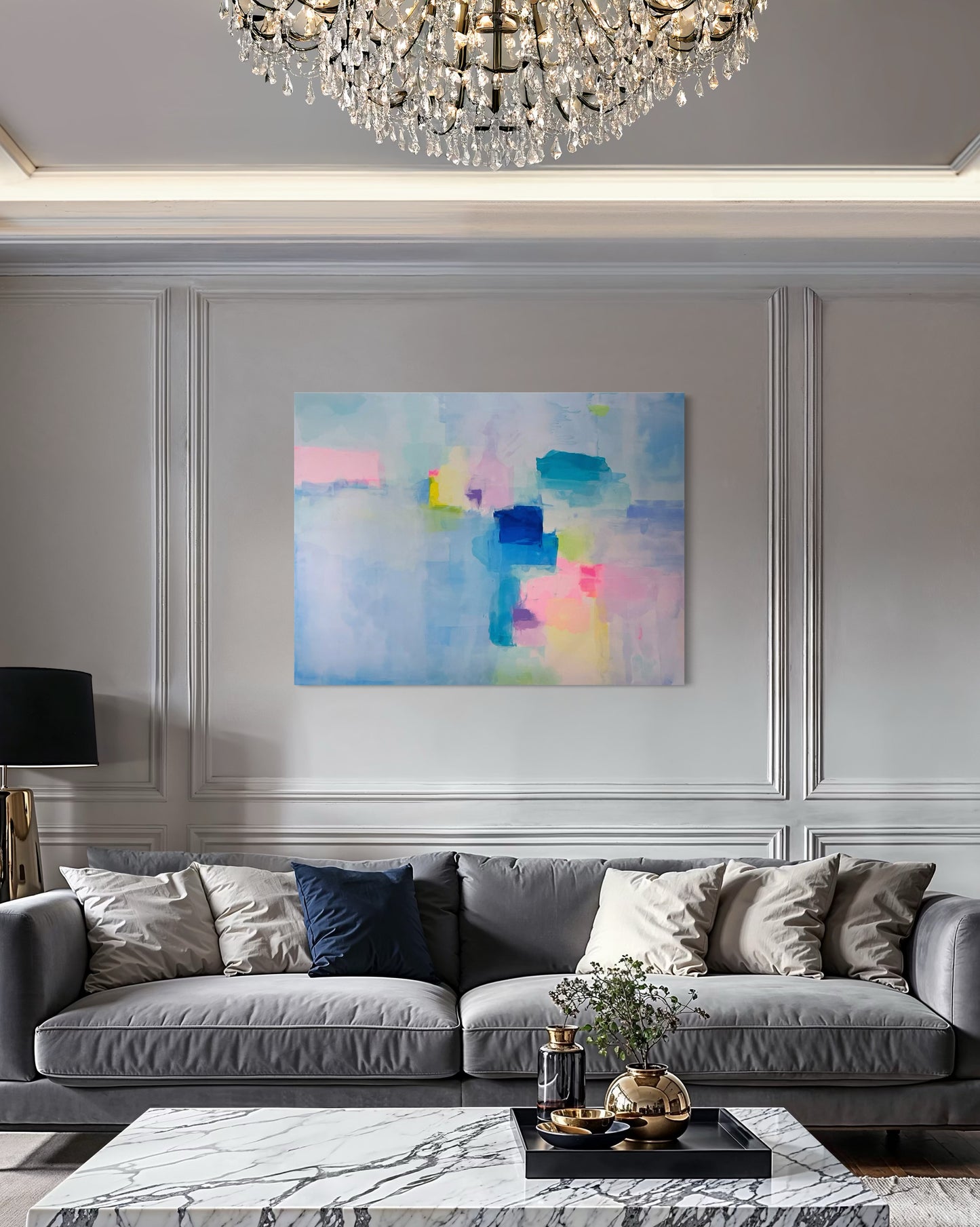 Modern living room with a gray sofa, colorful abstract painting, and chandelier.
