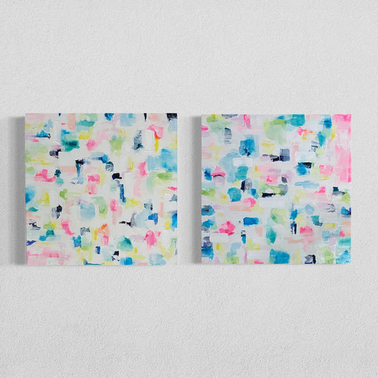 Two abstract pastel canvas paintings side by side on a white wall, featuring expressive brushstrokes in pink, blue, yellow, and green tones for modern home décor.