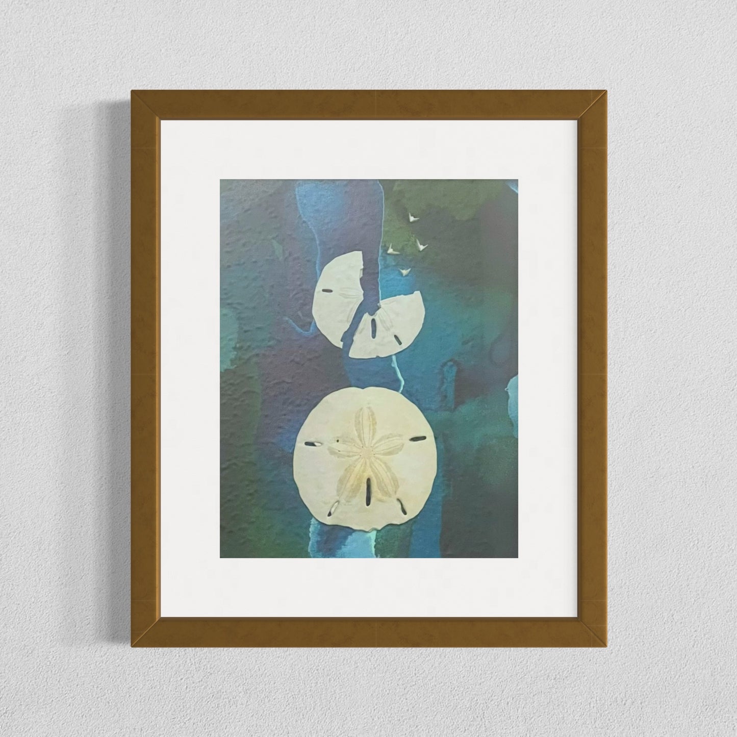 Framed mixed media artwork titled "Free Birds" featuring real sand dollars on an abstract blue and green ink background, with five white bird shapes emerging from a broken sand dollar.